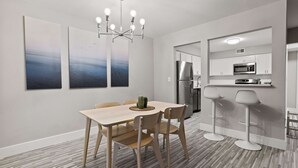 Une cuisine moderne avec des meubles blancs, des appareils en acier inoxydable et un coin bar avec des tabourets.