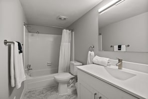 A modern bathroom with a bathtub, toilet, and vanity. - Welcoming 2BR 2BA Retreat With Modern Comforts (Rochester)