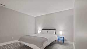 Une chambre à coucher avec un lit, une table de chevet et une lampe.