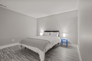 A bedroom with a bed, a nightstand, and a lamp. - Welcoming 2BR 2BA Retreat With Modern Comforts (Rochester)