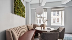 Un salon moderne avec un canapé aux lignes courbes, une table à manger ronde et deux chaises.