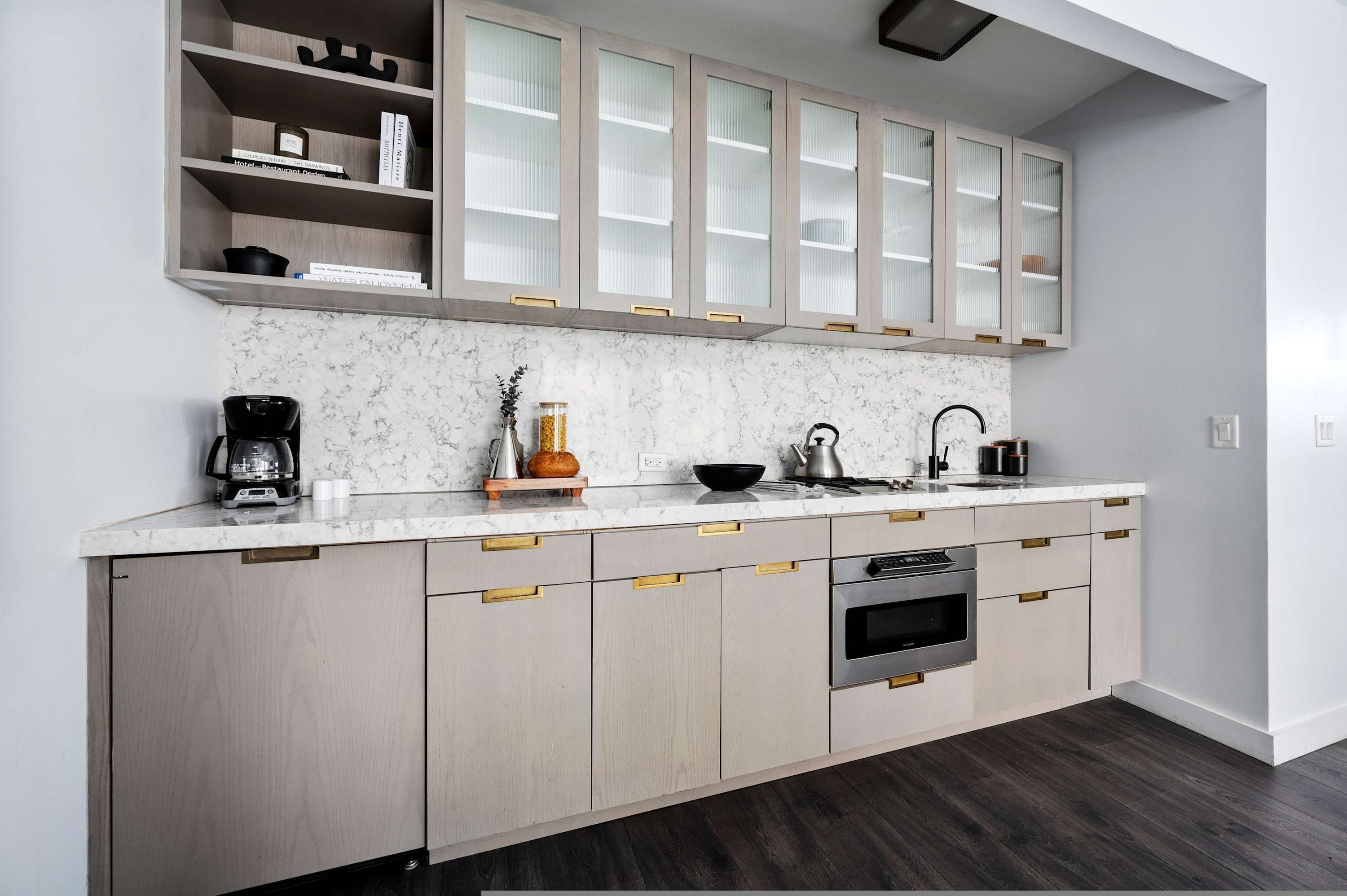 A modern kitchen with a marble countertop, wooden cabinets, and a built-in oven.