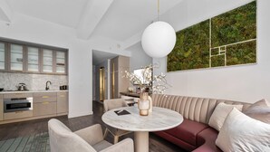 Une cuisine moderne dotée d’appareils électroménagers intégrés, un coin repas avec une table ronde et un salon avec un canapé et des fauteuils.