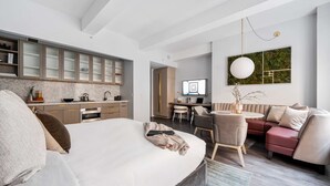 Une chambre d’hôtel moderne dotée d’un grand lit, d’un bureau, d’un canapé et d’un coin cuisine.