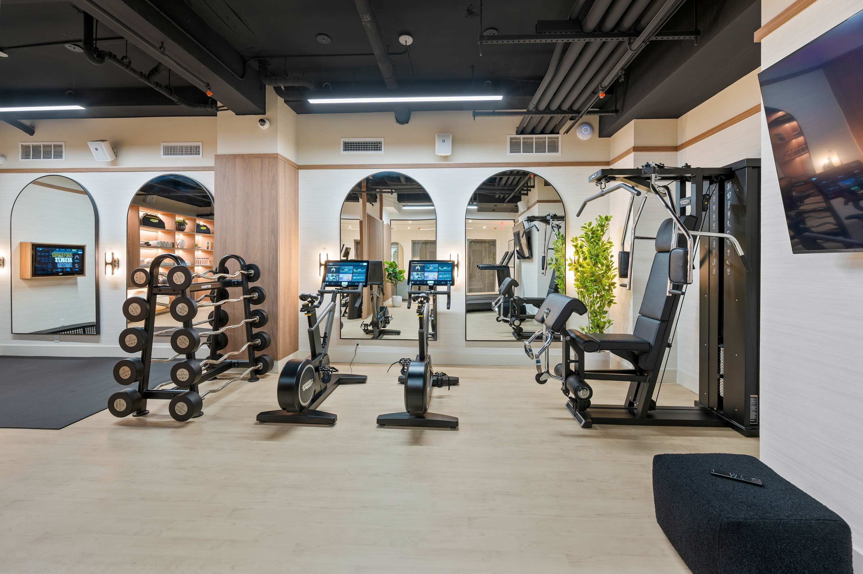 Een fitnessruimte met krachtapparatuur, cardio toestellen en spiegels.