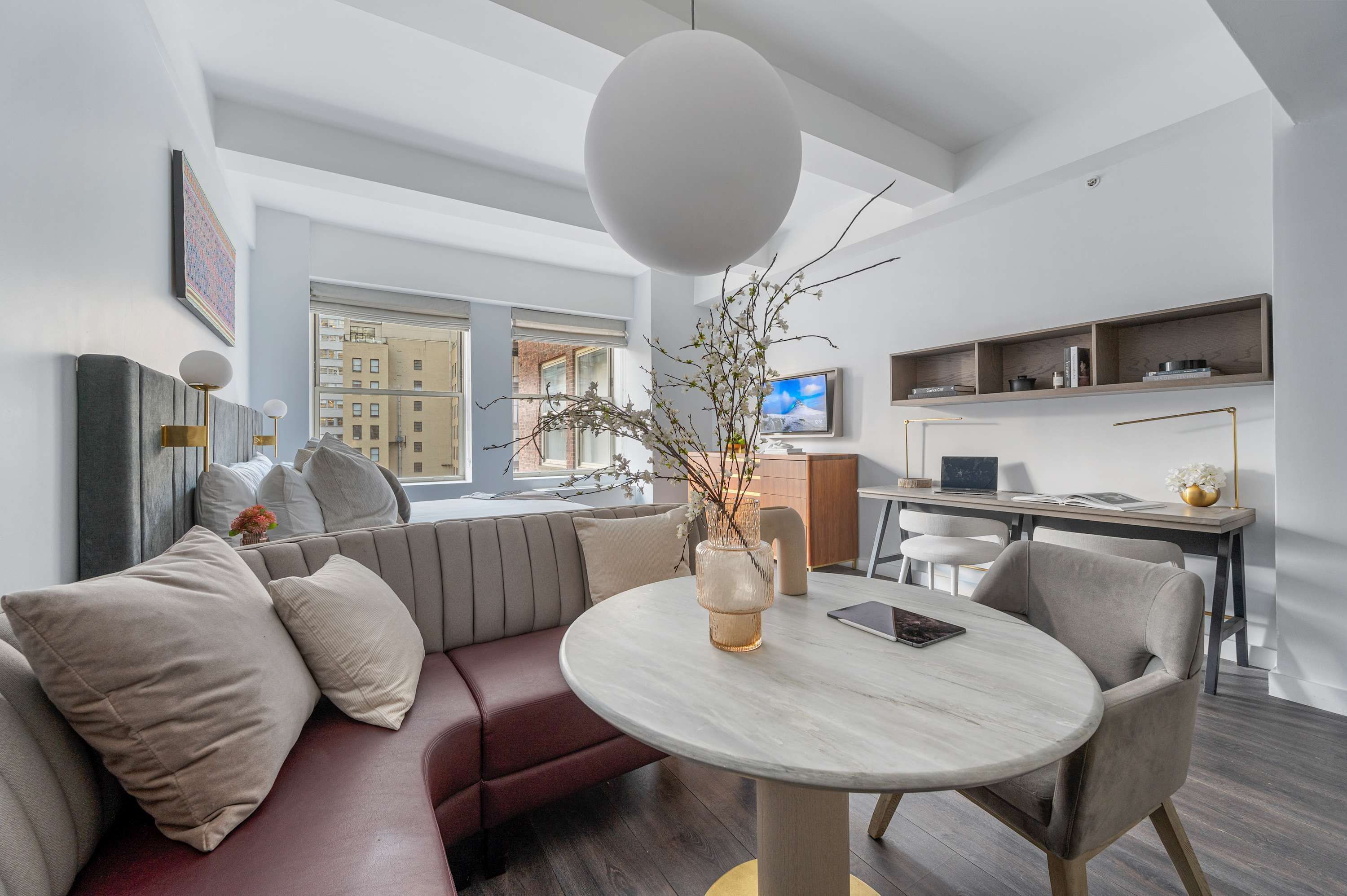 Ein modernes Wohnzimmer mit rundem Tisch, einer Couch und einem Fernseher im Hintergrund.