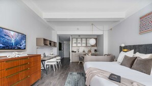 Ein modernes Hotelzimmer mit Bett, Schreibtisch und Küchenzeile.
