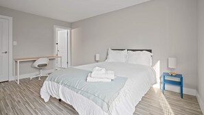 Une chambre bien rangée, avec un lit, une table de chevet, une chaise et un bureau.
