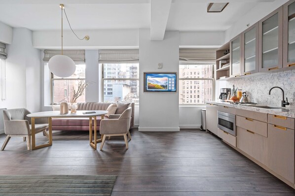 A modern kitchen with a marble countertop, built-in oven, and a large window. - 17john: Deluxe King Studio Apartment (New York)