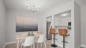 Eine moderne Küche mit weißen Schränken, einem Edelstahlkühlschrank und einem Barhocker.