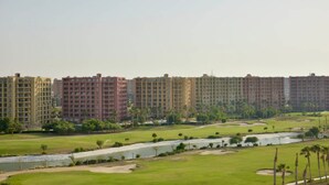 Un quartier résidentiel comprenant des immeubles d’habitation à étages élevés, un terrain de golf et un plan d’eau.