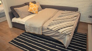 Une chambre moderne avec un canapé-lit, des coussins à rayures et un tapis à rayures.