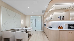 Ein modernes Hotelzimmer mit minimalistischem Design, ausgestattet mit einer gewölbten Holzanlage, einer Sitzecke mit Tisch und Stühlen sowie einem großen, abstrakten Wandbild.