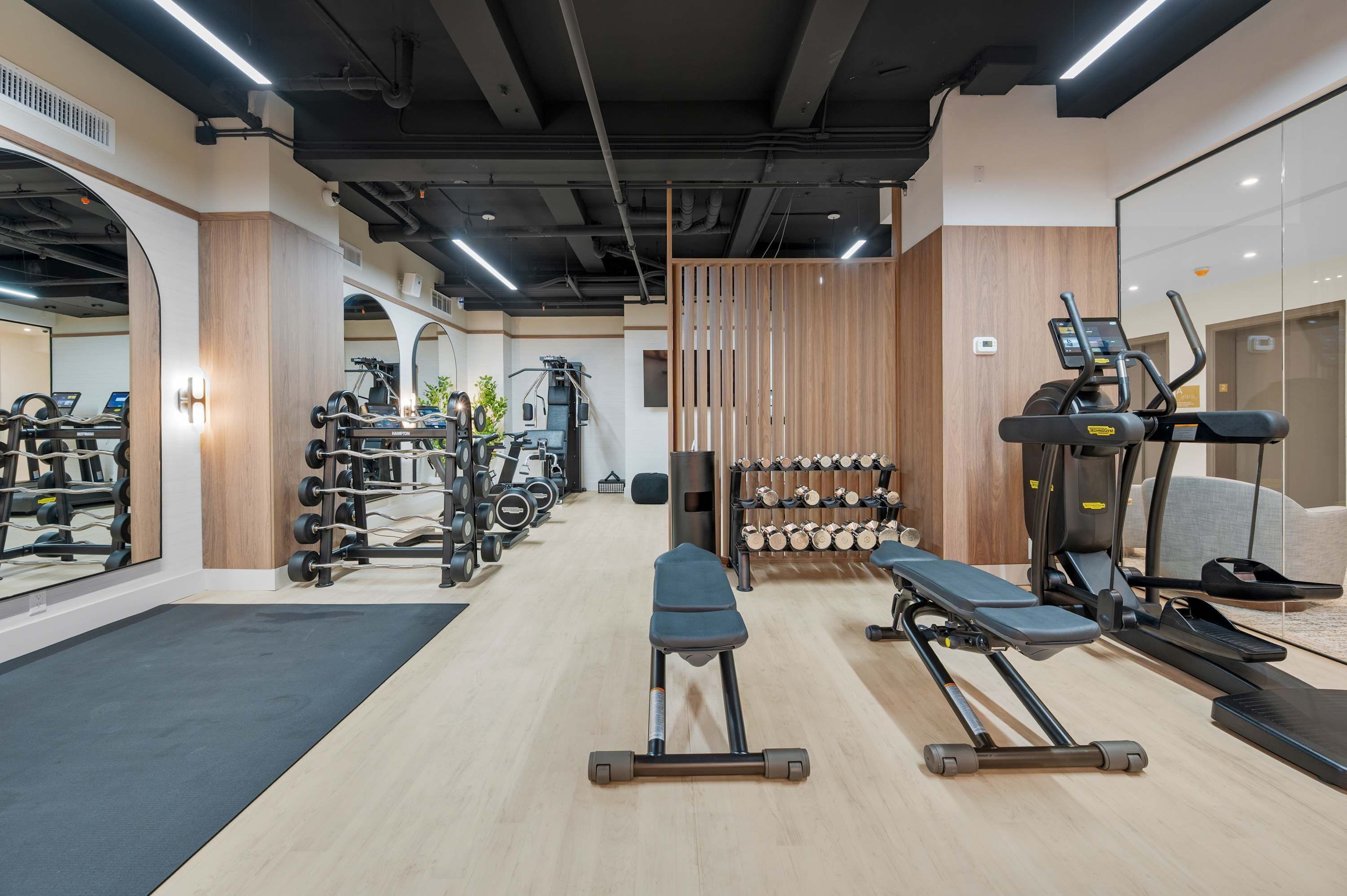 Un gimnasio con cintas de correr, máquinas de pesas y pesas libres.