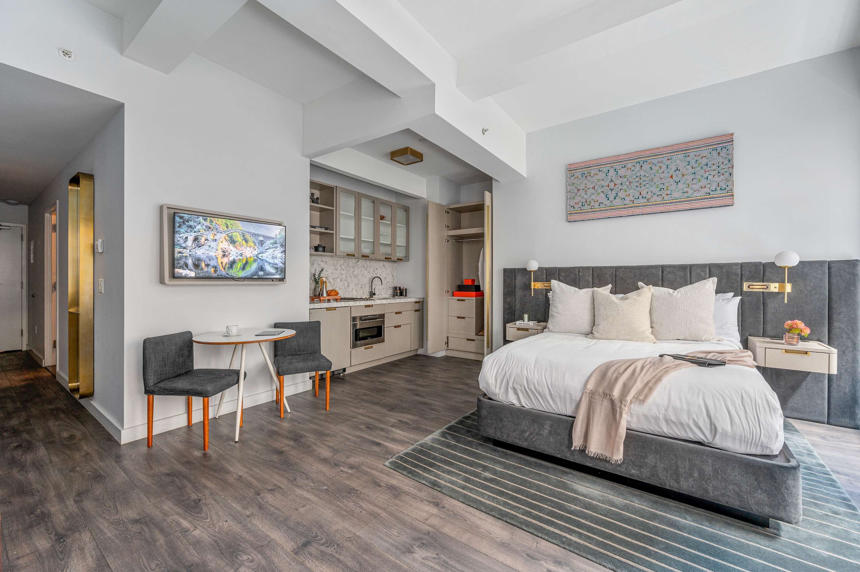 Een moderne slaapkamer met een groot bed, een bureau en een kitchenette.