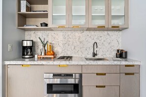 A kitchen with a marble backsplash, stainless steel appliances, and wooden cabinets. - 17john: Queen Studio Apartment - Disability Access (New York)