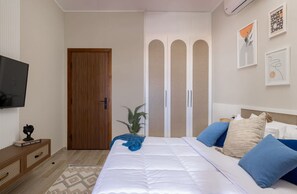 Una camera da letto con un letto, una televisione, un armadio e una pianta.