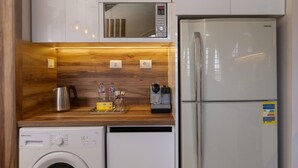 A compact kitchen with a washing machine, a refrigerator, and a microwave.