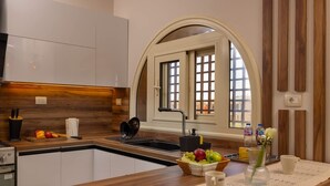 A modern kitchen with white cabinets, a wooden countertop, a built-in oven, and a window with a view.
