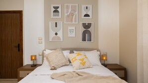 A bedroom with a bed, two bedside tables, a wooden door, and wall art.