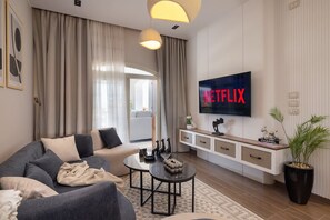 Un soggiorno moderno con divano, tavolino e televisore che mostra 'NETFLIX'.