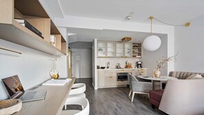 A modern kitchen with white cabinets, a dining area with a round table, and a living area with a sofa and chairs. - 17john: Junior King Studio (New York)
