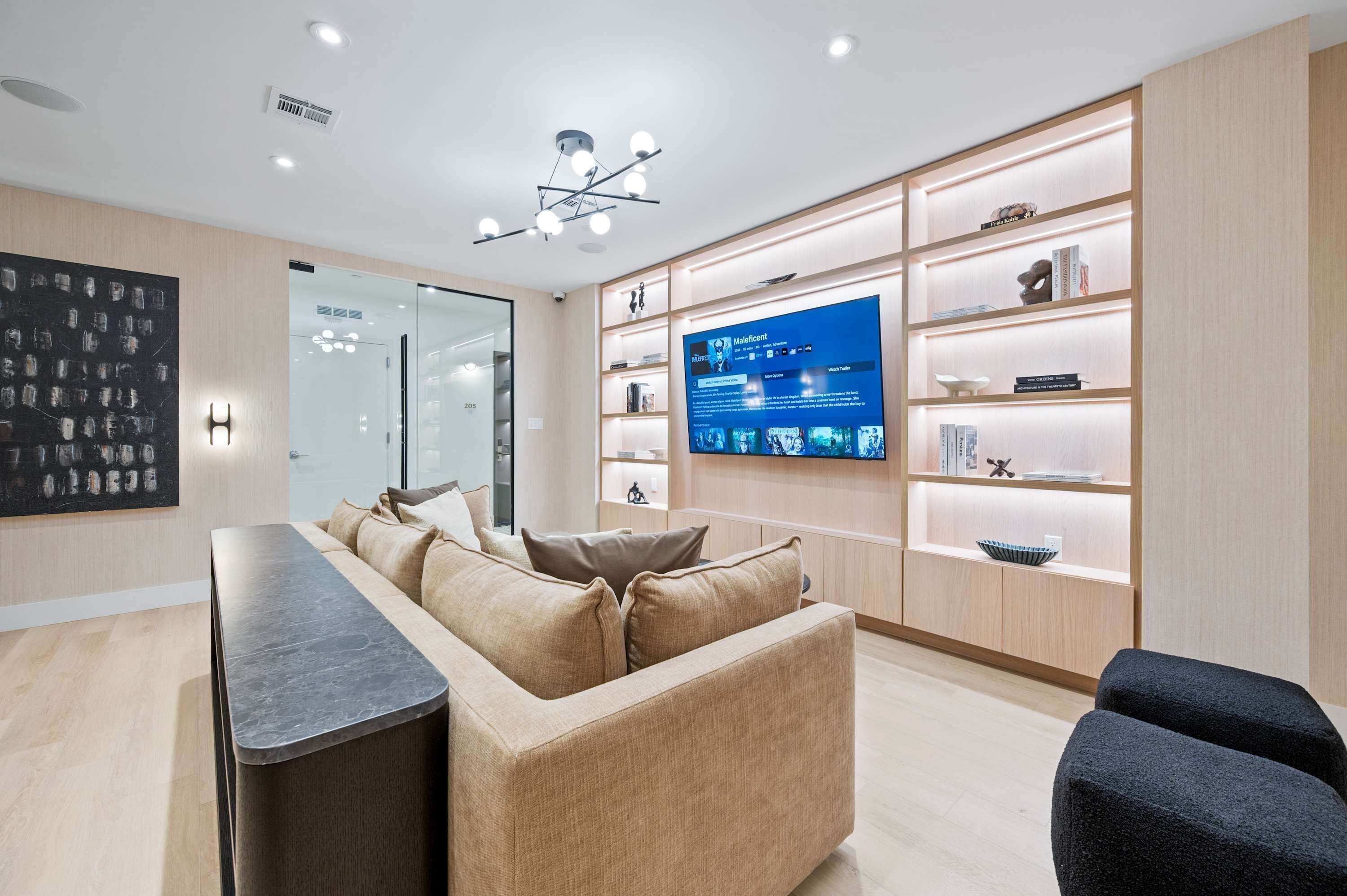A modern living room with a sofa, a coffee table, a TV, and built-in shelving with decorative items.