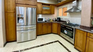A modern kitchen with wooden cabinets, stainless steel appliances, and a gas stove. - Family Friendly Villa New Cairo (New Cairo)