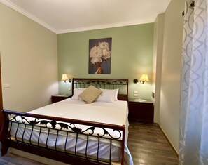 A neatly made bed with a headboard, two bedside lamps, a painting of flowers on the wall, and a patterned curtain. - Family Friendly Villa New Cairo (New Cairo)