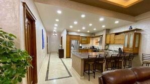 A modern kitchen with a central island, bar stools, and wooden cabinets. - Family Friendly Villa New Cairo (New Cairo)