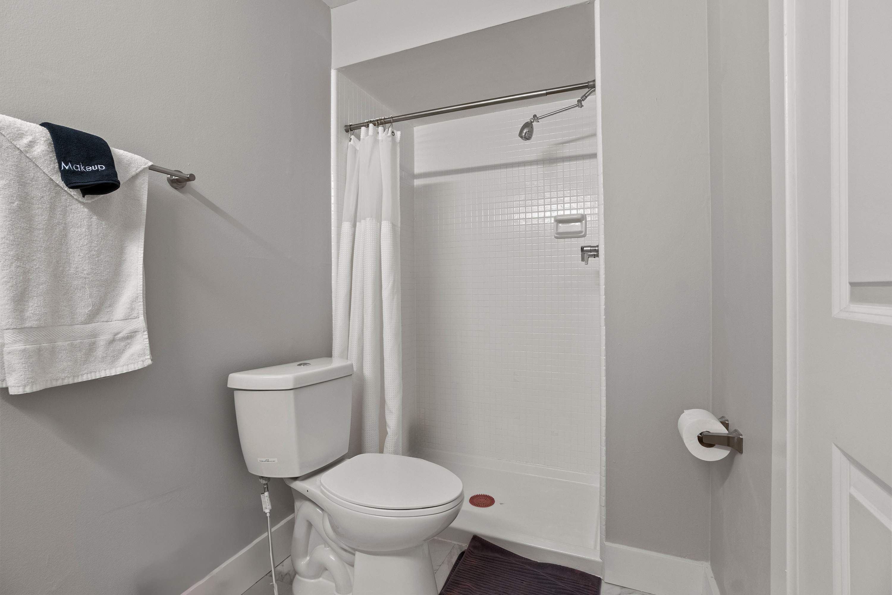 A bathroom with a toilet, a shower curtain, and a towel rack with a towel.