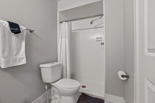 Un baño con inodoro, cortina de ducha y toallero con toalla.