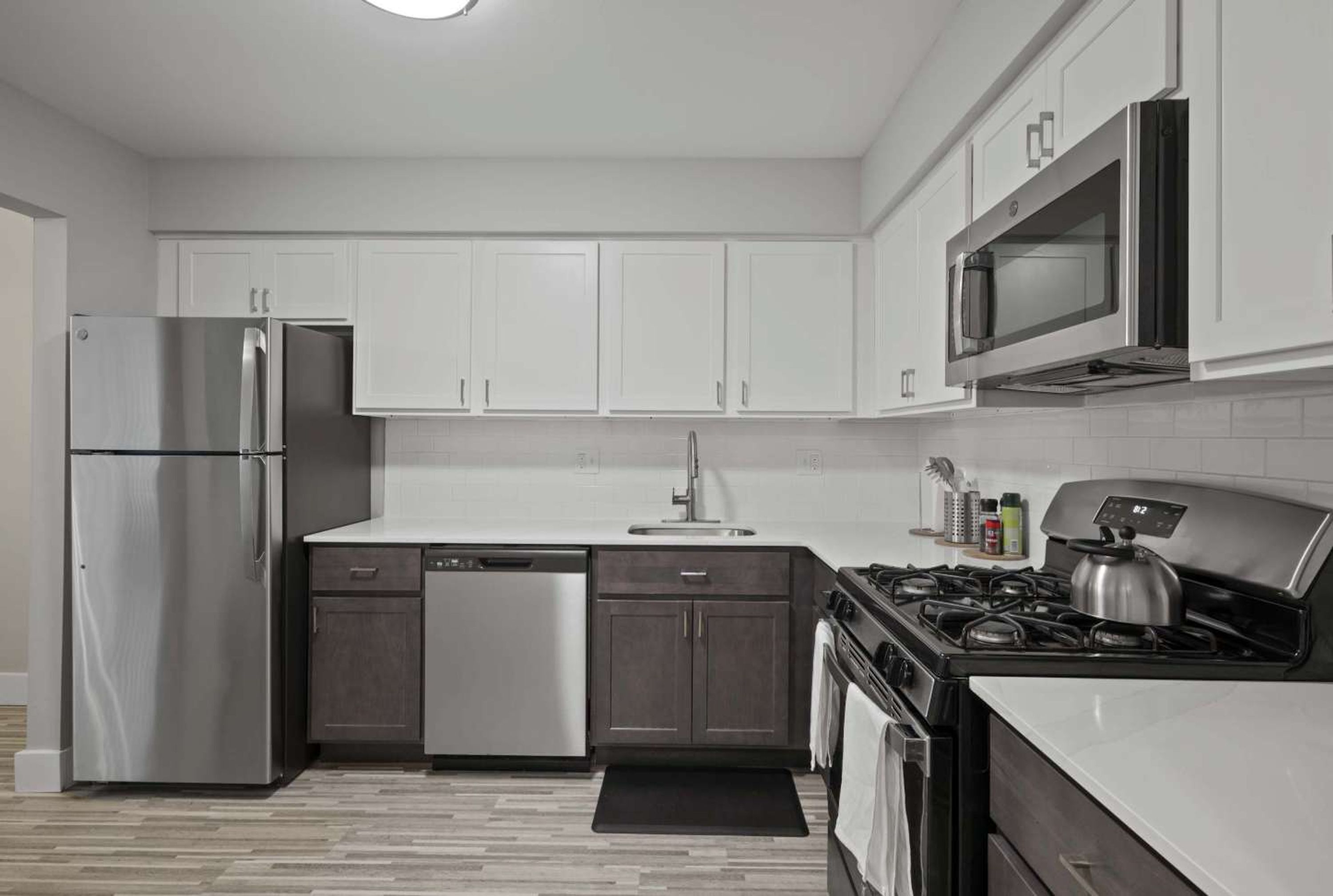 Une cuisine moderne avec des meubles blancs, des appareils en acier inoxydable et une cuisinière noire.