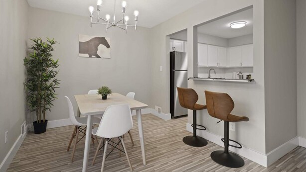 A modern kitchen with white cabinets, a black refrigerator, and a built-in island with bar stools. - Inviting 2BR 2BA Unit in Rochester Hills (Rochester)
