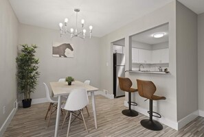 A modern kitchen with white cabinets, a black refrigerator, and a built-in island with bar stools. - Inviting 2BR 2BA Unit in Rochester Hills (Rochester)
