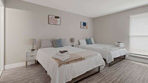 A bedroom with two beds, a nightstand, a lamp, and artwork on the wall. - Inviting 2BR 2BA Unit in Rochester Hills (Rochester)