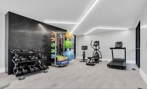 A modern gym with exercise equipment, a treadmill, and a wall-mounted rack of dumbbells. - Inviting 2BR 2BA Unit in Rochester Hills (Rochester)