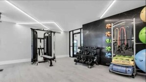 A gym with exercise equipment, a squat rack, and a wall-mounted rack with weights. - Inviting 2BR 2BA Unit in Rochester Hills (Rochester)