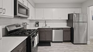A modern kitchen with white cabinets, stainless steel appliances, and a black countertop. - Tranquil 2BR 2BA Getaway for the Family (Rochester)