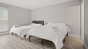 A modern hotel room with two beds, a grey headboard, and a wooden floor. - Tranquil 2BR 2BA Getaway for the Family (Rochester)