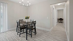 A dining area with a table and chairs, a chandelier, and a vase with flowers. - Comfortable 2BR 2BA Home Away From Home (Rochester)