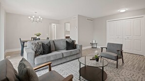 A modern living room with a grey sofa, a round coffee table, and a grey armchair. - Comfortable 2BR 2BA Home Away From Home (Rochester)