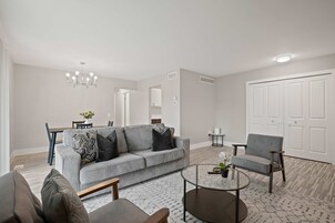 Una sala moderna con un sofá gris, una mesa de centro redonda y un sillón gris.