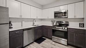 A modern kitchen with stainless steel appliances, white cabinets, and a black countertop. - Beautiful 2BR 2BA Apartment With Modern Design (Rochester)