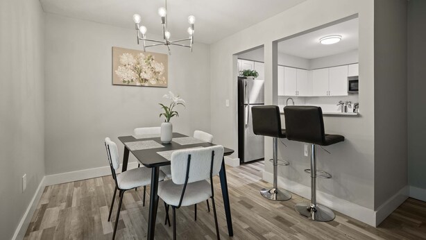 A modern dining area with a chandelier, a vase of flowers, and a painting on the wall. - Beautiful 2BR 2BA Apartment With Modern Design (Rochester)