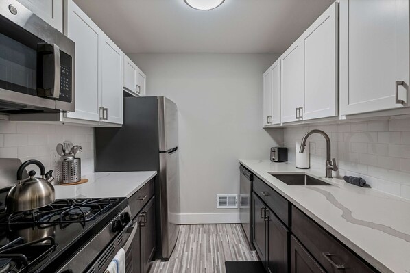 A modern kitchen with white cabinets, stainless steel appliances, a gas stove, and a sink.