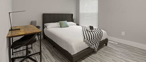 A bedroom with a bed, a desk, and a chair.