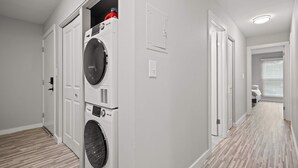 A laundry room with stacked washers and dryers, a wooden floor, and white walls. - Family Friendly 2BR 2BA in the City (Rochester)