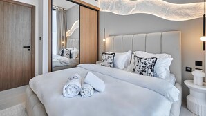 Ein modernes Hotelzimmer mit einem großen Bett, einem Holzschrank, einem Spiegel und einer einzigartigen Deckenleuchte.