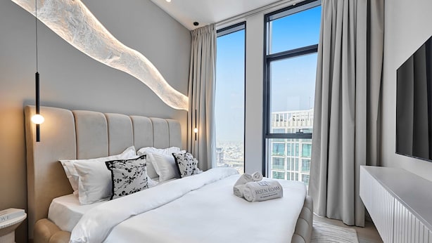 Ein modernes Hotelzimmer mit einem großen Bett, einem Fernseher und Blick auf die Stadt.